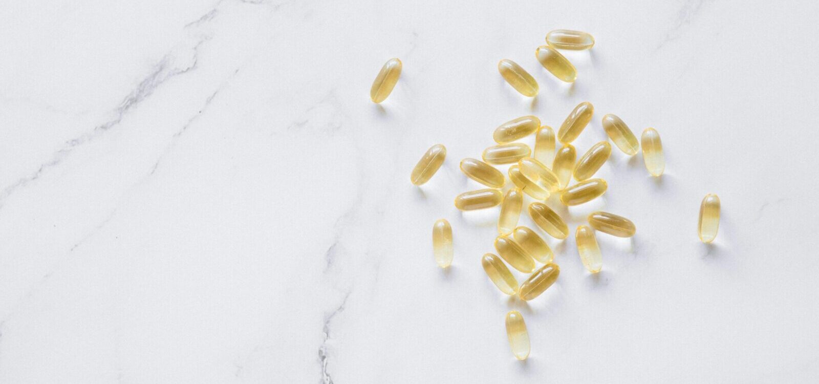 A group of translucent capsules arranged on a marble surface, offering a minimalist aesthetic.